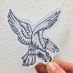 a hand holding up a sticker with an eagle on it