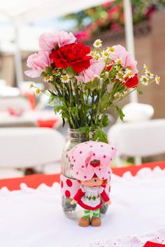 a vase filled with flowers sitting on top of a white table covered in pink and red flowers