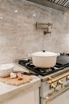 a stove top oven sitting inside of a kitchen next to a cutting board and knife