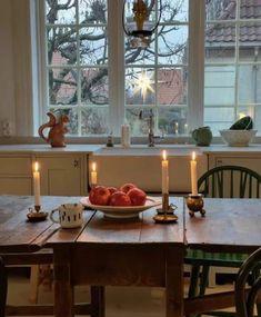 a bowl of fruit sitting on top of a wooden table next to a candle holder