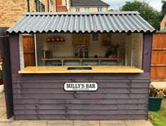 an outdoor bar with a metal roof and wooden counter top on the side of a house