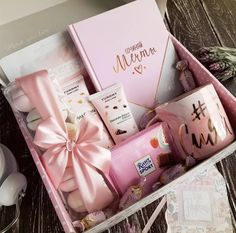 a pink gift box filled with personal care items on top of a wooden table next to a coffee mug