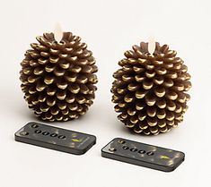 two pinecone shaped candles with remote controls next to each other on a white surface