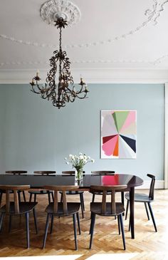 a dining room with a chandelier hanging from the ceiling and chairs around it