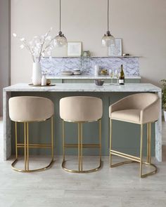 two bar stools sitting in front of a marble counter top with gold trimming