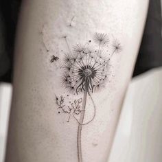 a woman's thigh with a dandelion tattoo on it