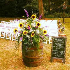 a wooden barrel filled with flowers next to a sign