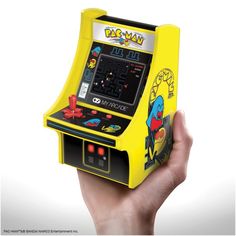 a person holding up a yellow arcade machine in front of a white background with the words, pac - man on it