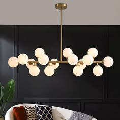 a modern chandelier hanging from the ceiling in a living room with black walls