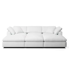 a white couch with four pillows on it's back end and one arm facing the camera