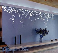 the wall is decorated with white flowers and butterflies on it's side, along with an entertainment center