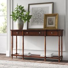 a wooden table with two drawers and a potted plant on it in front of a window