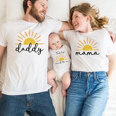 a man and woman laying on top of a bed with their baby wearing matching shirts