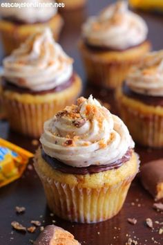 cupcakes with white frosting and sprinkles sitting on a table