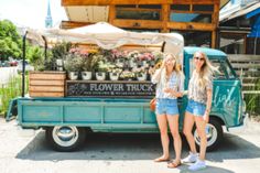 two women standing in front of a flower truck