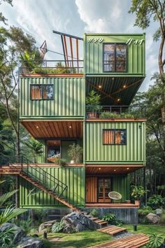 green shipping container home in the woods with stairs leading up to it's second floor