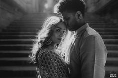 a man and woman standing next to each other in front of some stairs