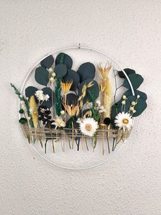 an arrangement of flowers and plants on a white wall mounted in a circular glass frame