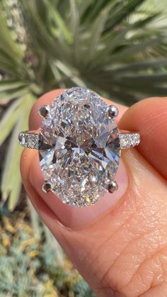 a close up of a person's hand holding a ring with a diamond in it