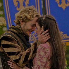 a man and woman hugging each other while standing in front of a blue sign that says'game of thrones '