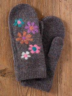 an oven mitt with flowers on it sitting on top of a wooden floor next to a wall