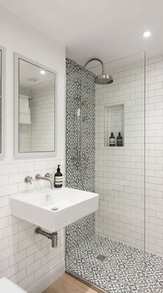 a white bathroom with black and white tile on the floor, shower stall and sink