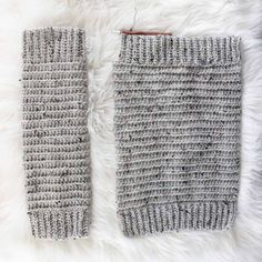 two gray knitted arm warmers sitting on top of a white rug