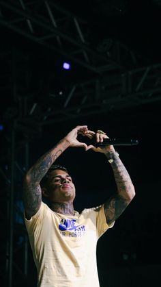 a man with tattoos on his arm holding a microphone up to the air while standing in front of a crowd