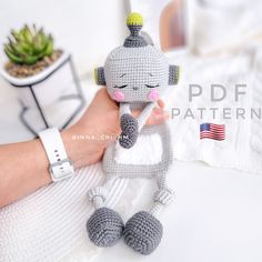 a hand holding a small crocheted gray and white doll with an american flag on it