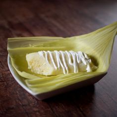 a banana split in half sitting on top of a wooden table with white icing