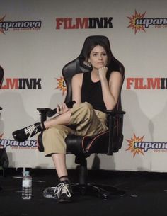 a woman sitting in a chair with her hand on her chin