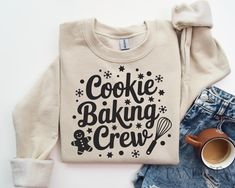 a sweater with the words cookie baking crew on it next to some denim shorts and a cup of coffee