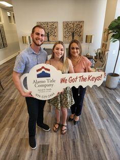 two women and a man holding a sign that says we got the keys in front of them