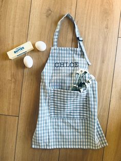 a blue and white gingham apron with flowers in it next to an egg carton