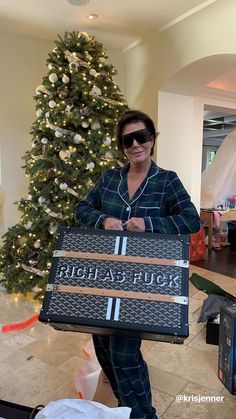 a woman is holding a large suitcase in front of a christmas tree with the words rich and fabulous written on it