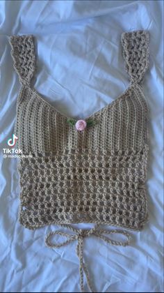 a crocheted top with a flower on the front and side, tied at the bottom