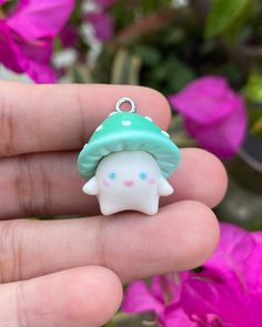 a hand holding a tiny white and green mushroom charm