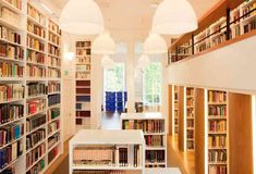 a room filled with lots of books on top of white shelves next to each other