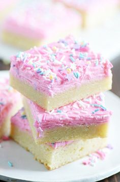 three pieces of cake with pink frosting and sprinkles stacked on top of each other