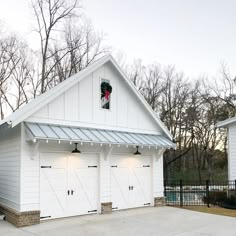 two white garages with lights on the roof and one has a christmas wreath hanging from it