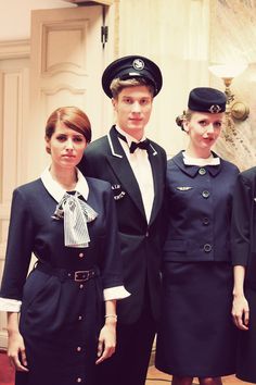 four people dressed in airline uniforms standing next to each other