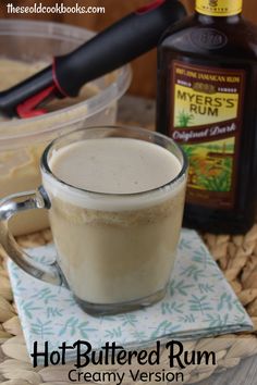 hot buttered rum in a glass mug on a napkin next to a bottle of syrup