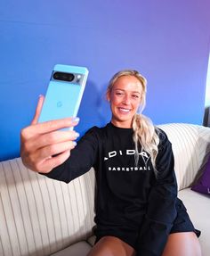 a woman sitting on a couch taking a selfie with her phone