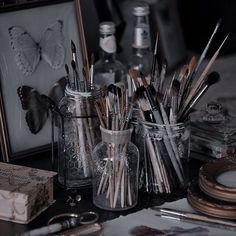 there are many brushes and other things in the glass jar on the table with it