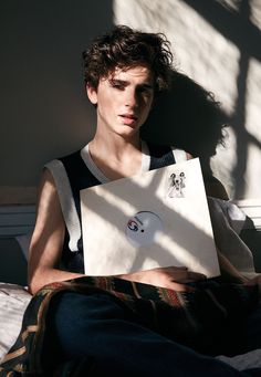 a young man sitting on a bed holding a laptop