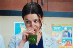 a woman in a lab coat holding a green drink