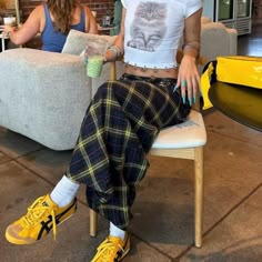 a woman sitting in a chair with her legs crossed and wearing yellow shoes, holding a cup