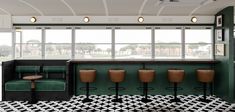 an empty bar with green chairs and black and white flooring in front of large windows