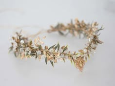 a gold headband with flowers and leaves on it's side, sitting on a white surface