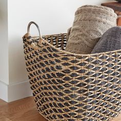 a woven basket with handles is sitting on the floor